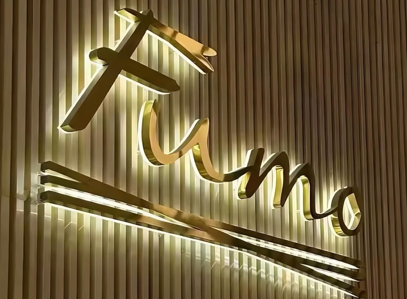 Gold stainless steel 3D LED letters with halo effect — Fumo restaurant illuminated sign mounted on a slatted wall